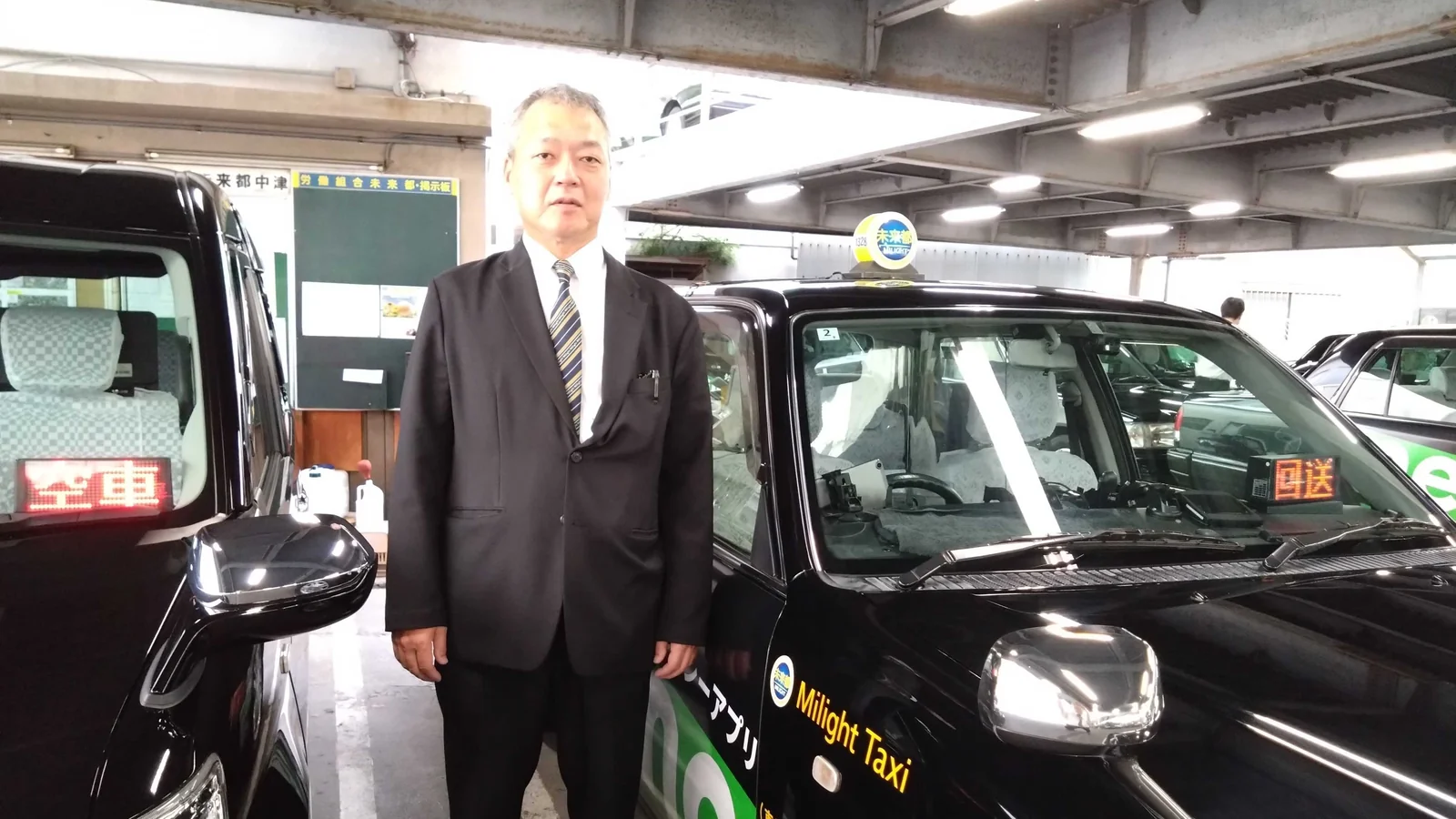車庫でタクシーの横に立つM.T.さん