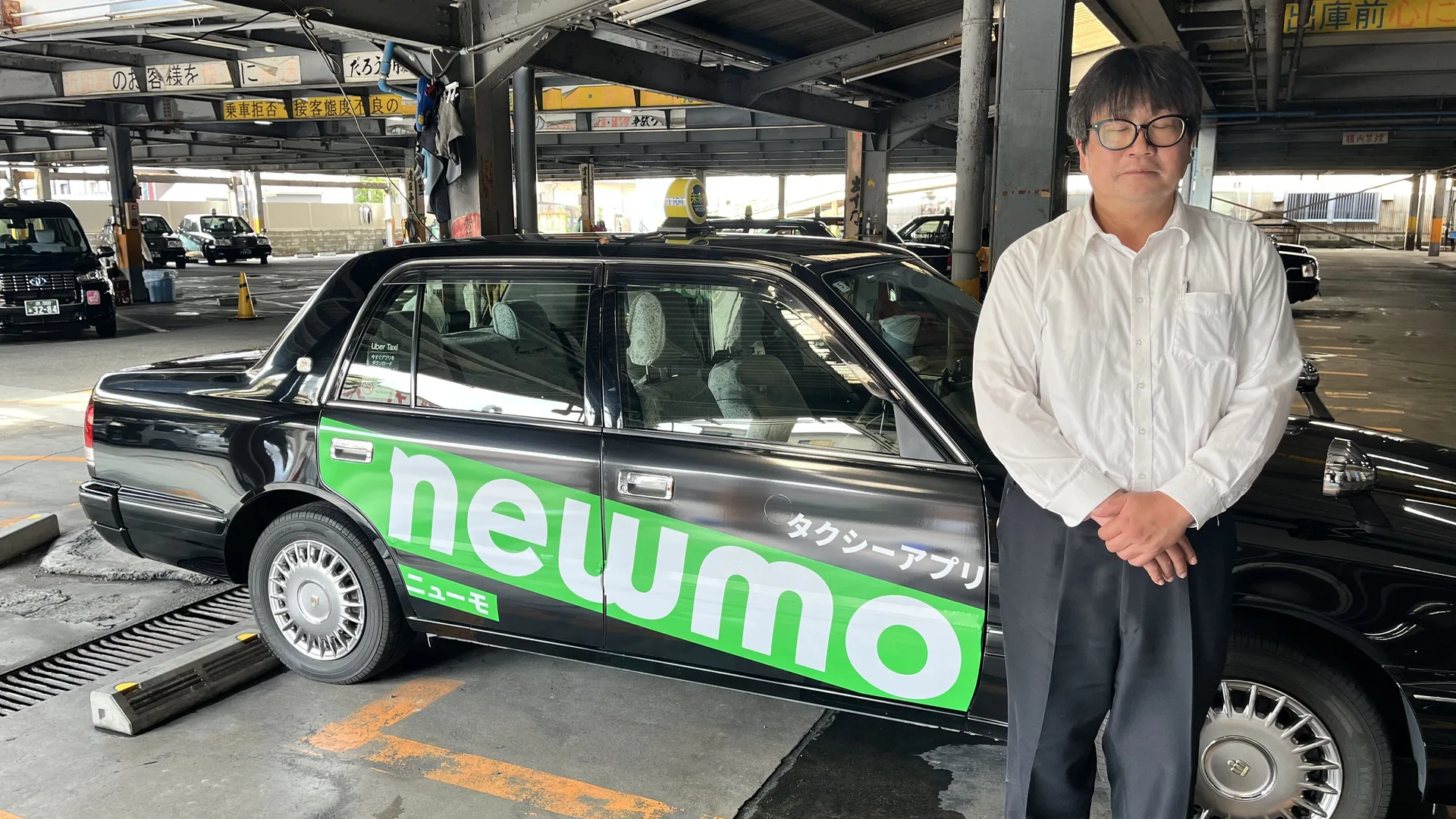 車庫でタクシーの横に立つS.M.さん