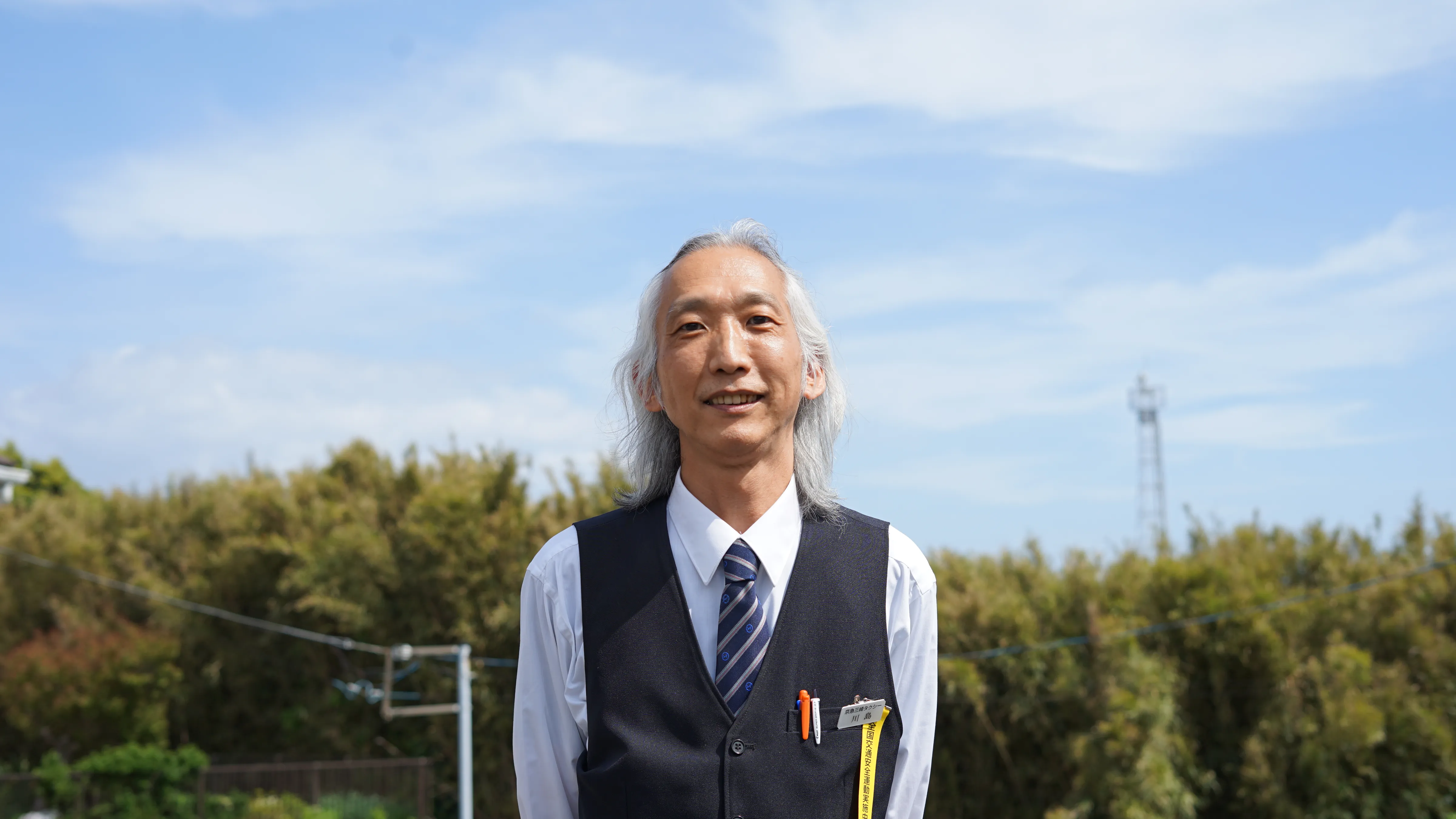 青空の下に立つK.K.さん