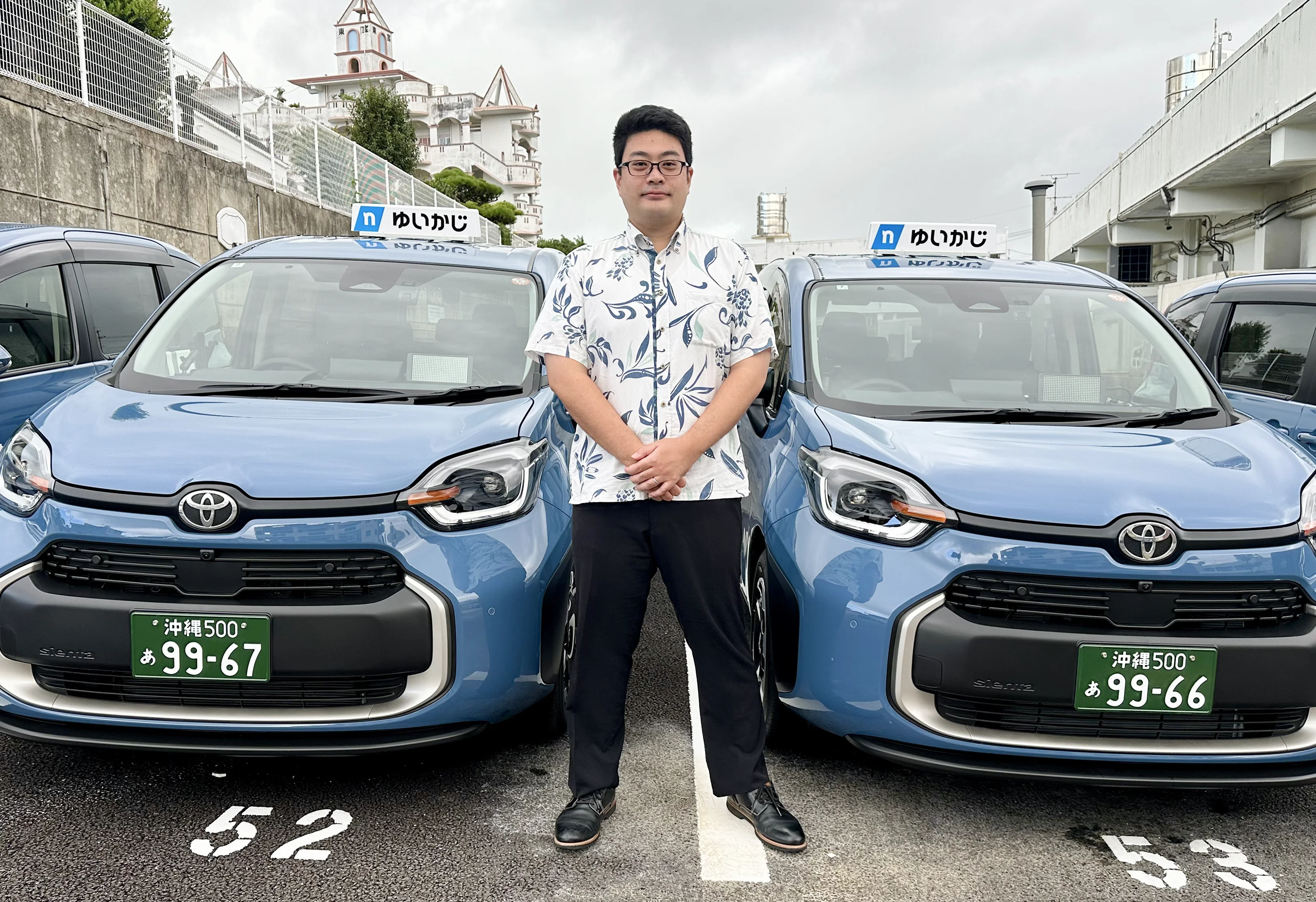 営業所の駐車場でタクシーの前に立つM.K.さん